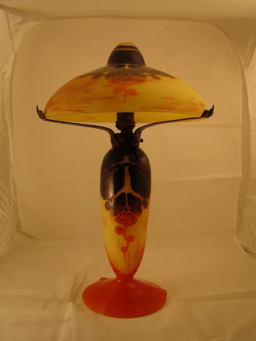 Lampe antique en verre signé avec des détails jaune et rouge.