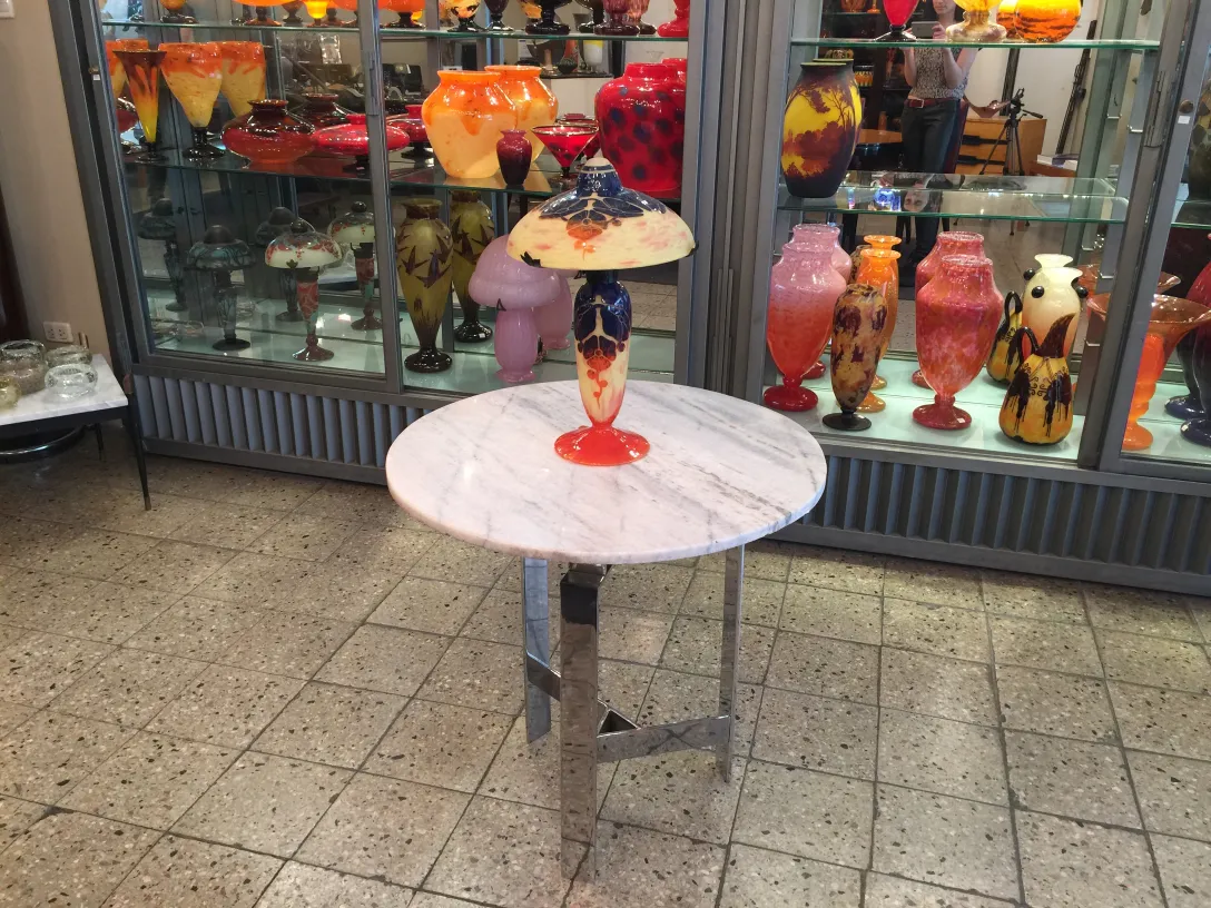 Antigo vidro assinado Le Verre com desenhos coloridos. Vitrine com outros itens antigos.