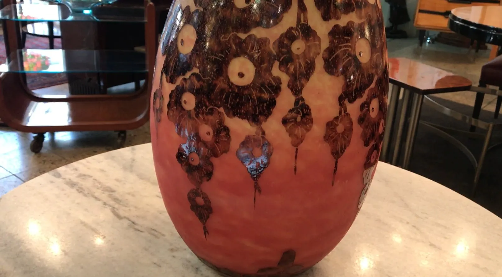 Vaso di vetro antico firmato Le Verre, con motivi floreali neri su sfondo rosso. Mobili d'epoca sullo sfondo.