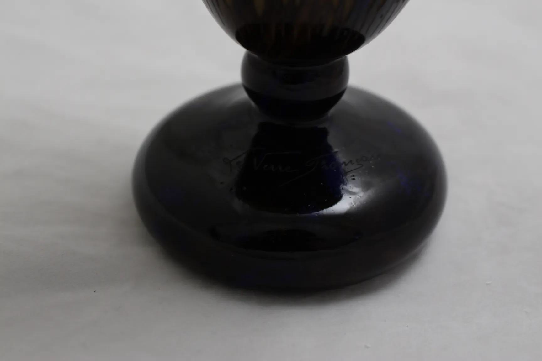 detalhe de uma base de vidro assinado le verre em cor escura