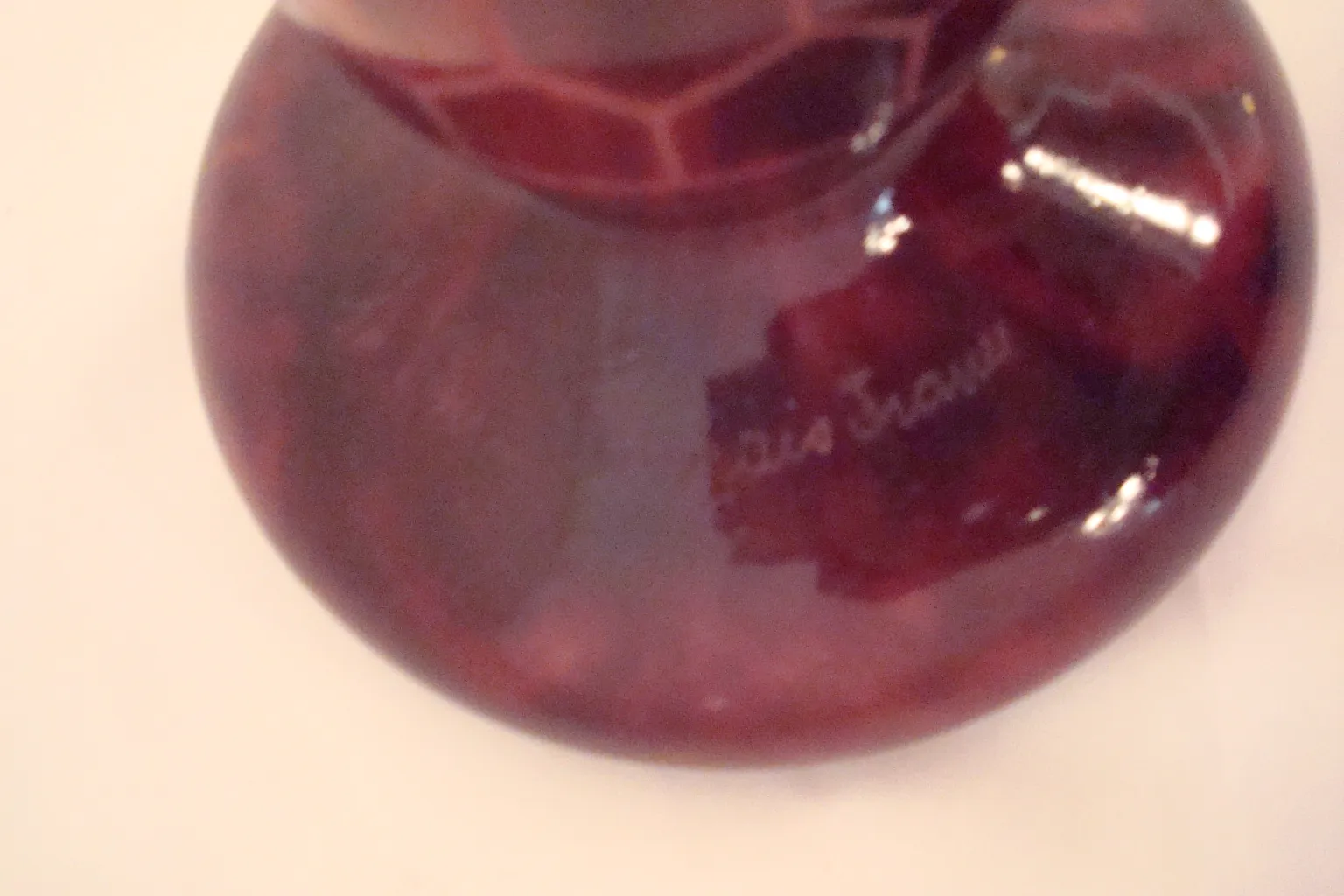 Antique signed glass with decorative pattern in red tones.