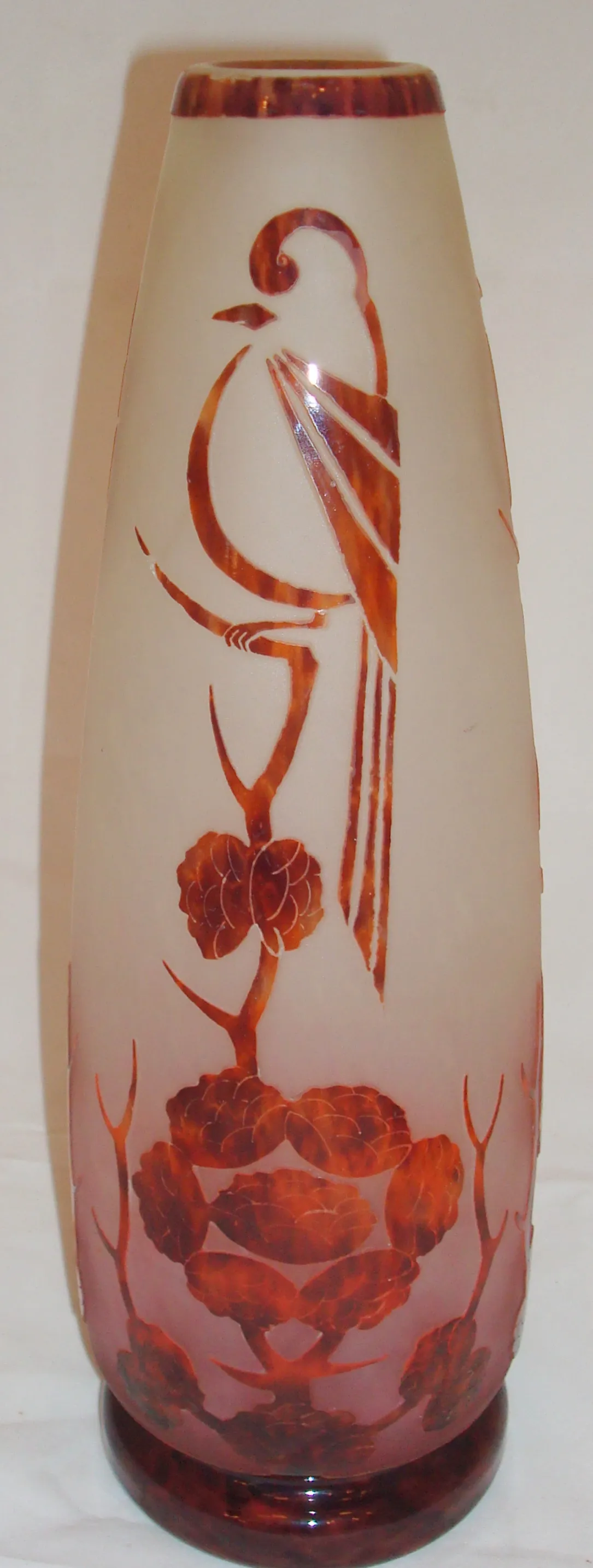 Vaso in vetro con design scolpito di uccelli e fiori in tonalità ambra, fondo crema.