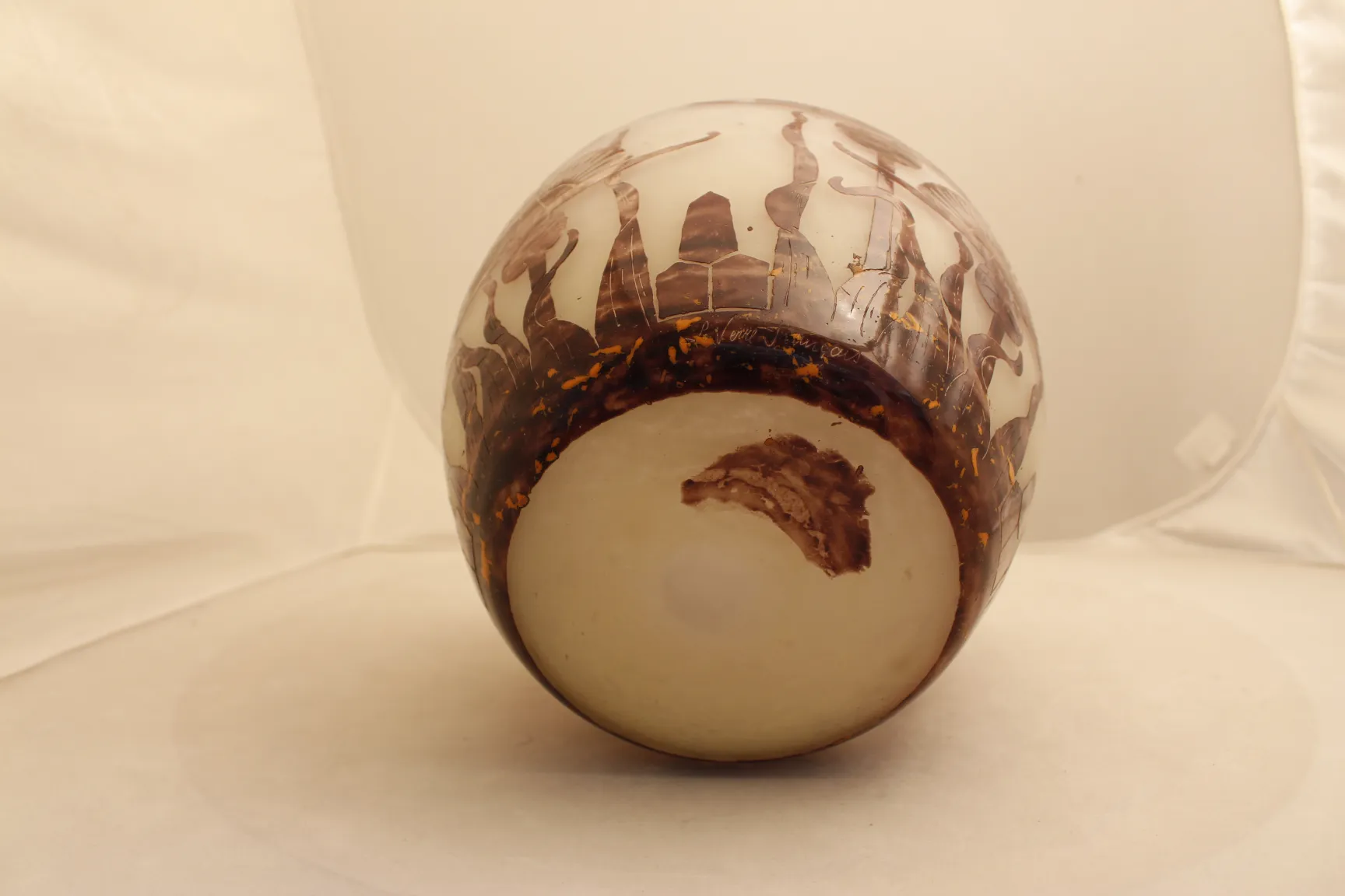 Vidro antigo assinado Le Verre com detalhes artísticos e fundo claro.