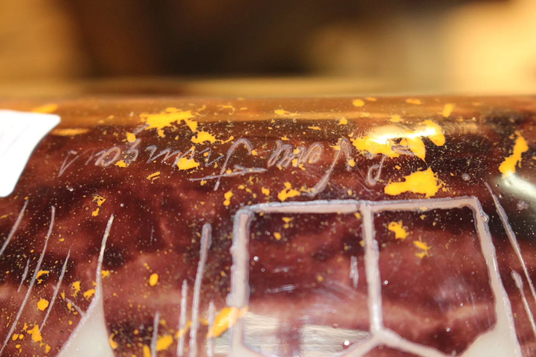 Vidro antigo assinado com detalhes amarelos e marrons.