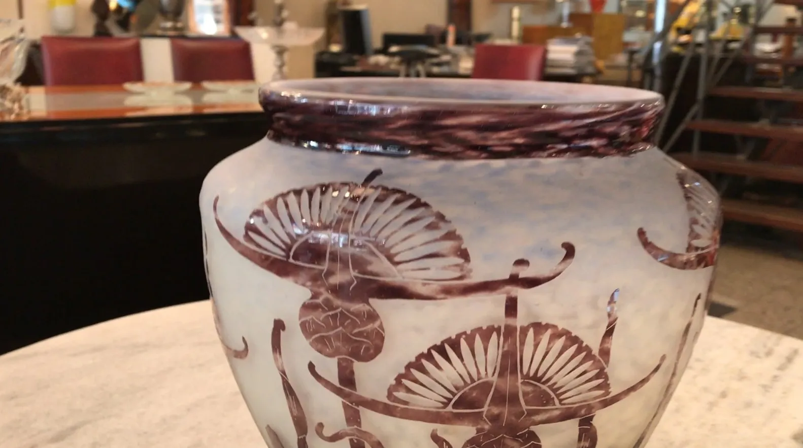 Vista detallada de antigüedad, vaso de vidrio firmado con diseño floral y fondo claro.