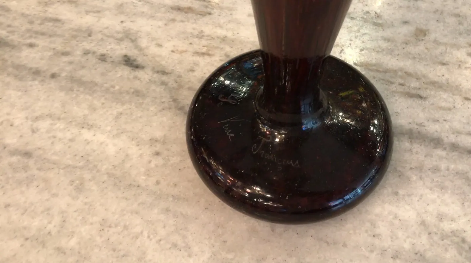 Vue détaillée d'un verre ancien signé, avec un fond clair.