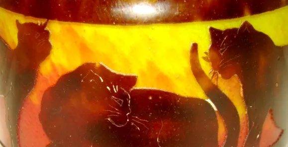 Signiertes Glas mit Katzenmotiv in warmen Farben.