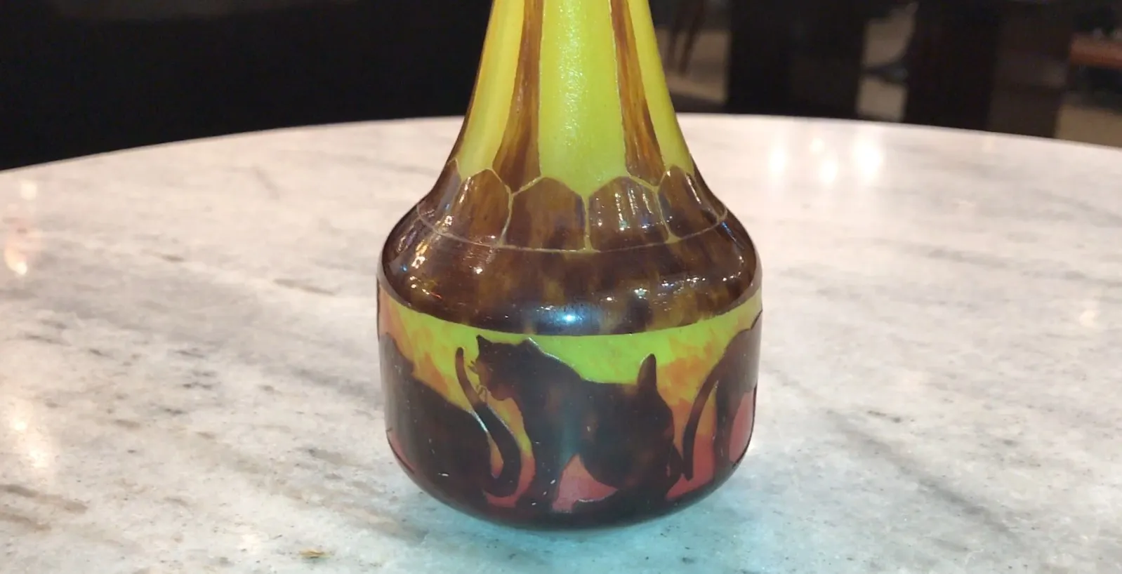 ग्लास पर हस्ताक्षरित Le Verre में बिल्ली के डिज़ाइन और गहरे पृष्ठभूमि पर गर्म रंग