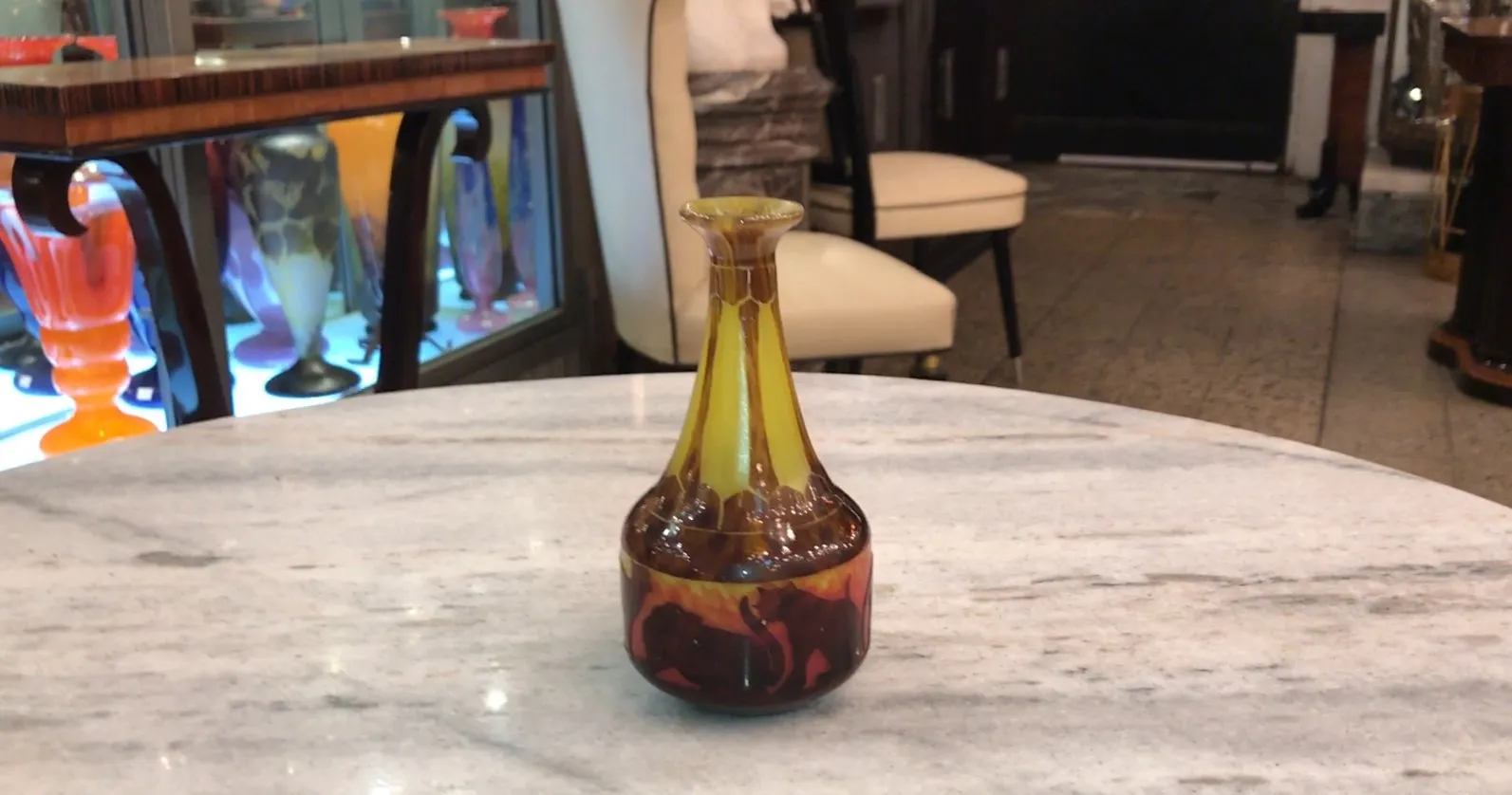 botella de vidrio marrón con diseño de elefantes en fondo naranja, sobre mesa de mármol