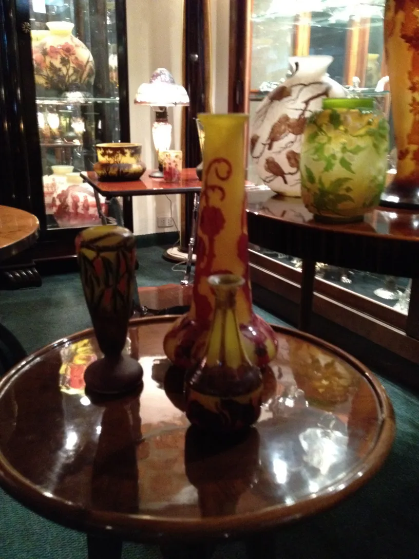 Glass signed Le Verre on antique table, many vases in the background.