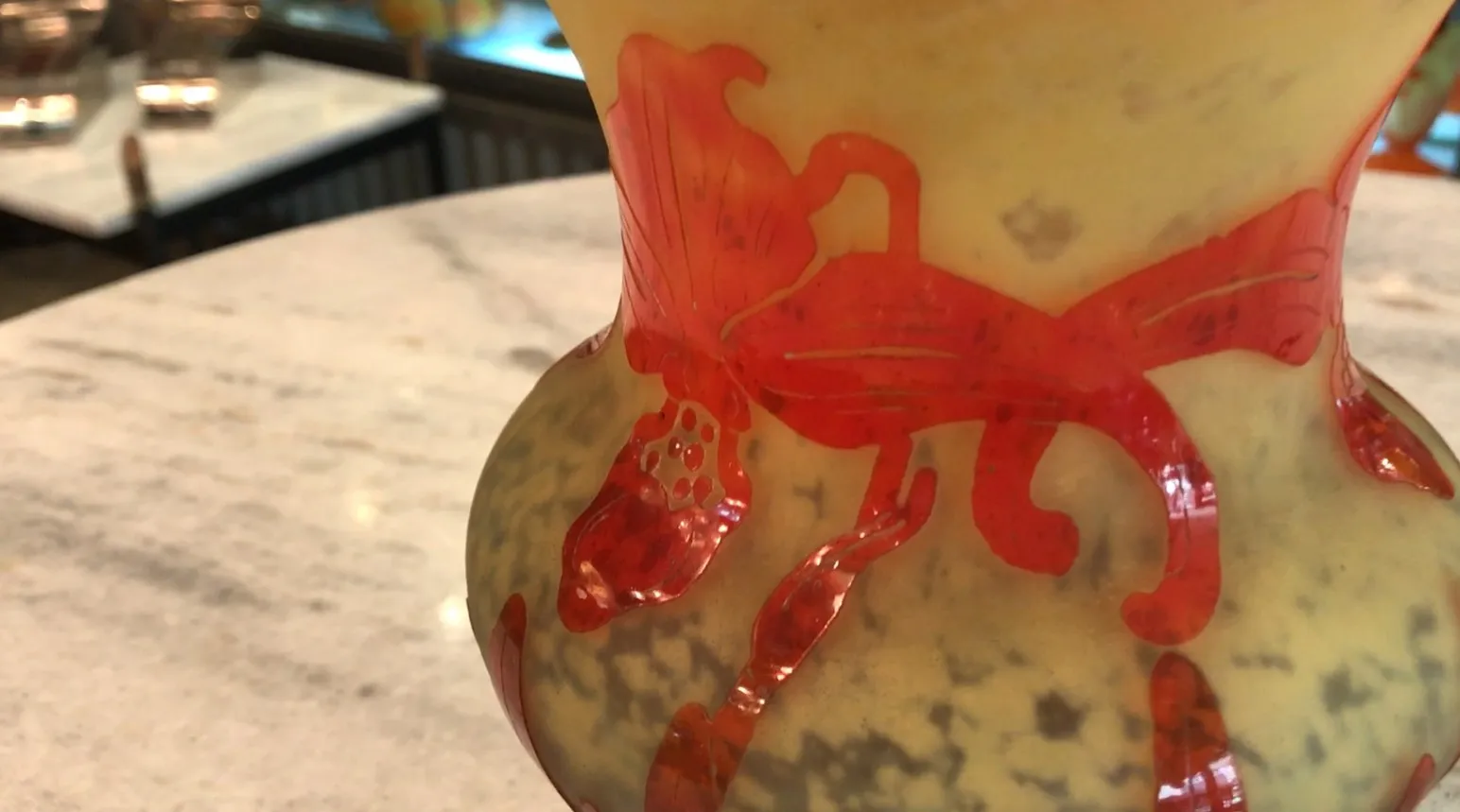 Signed glass Le Verre with decorative red details and a light background placed on a table.