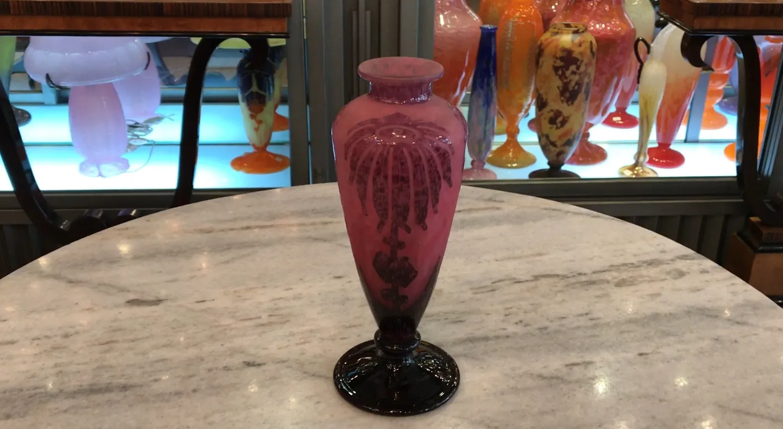 Signed glass vase in pink with colorful background.
