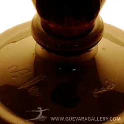 Vidro assinado Le Verre com detalhes decorativos em fundo claro.