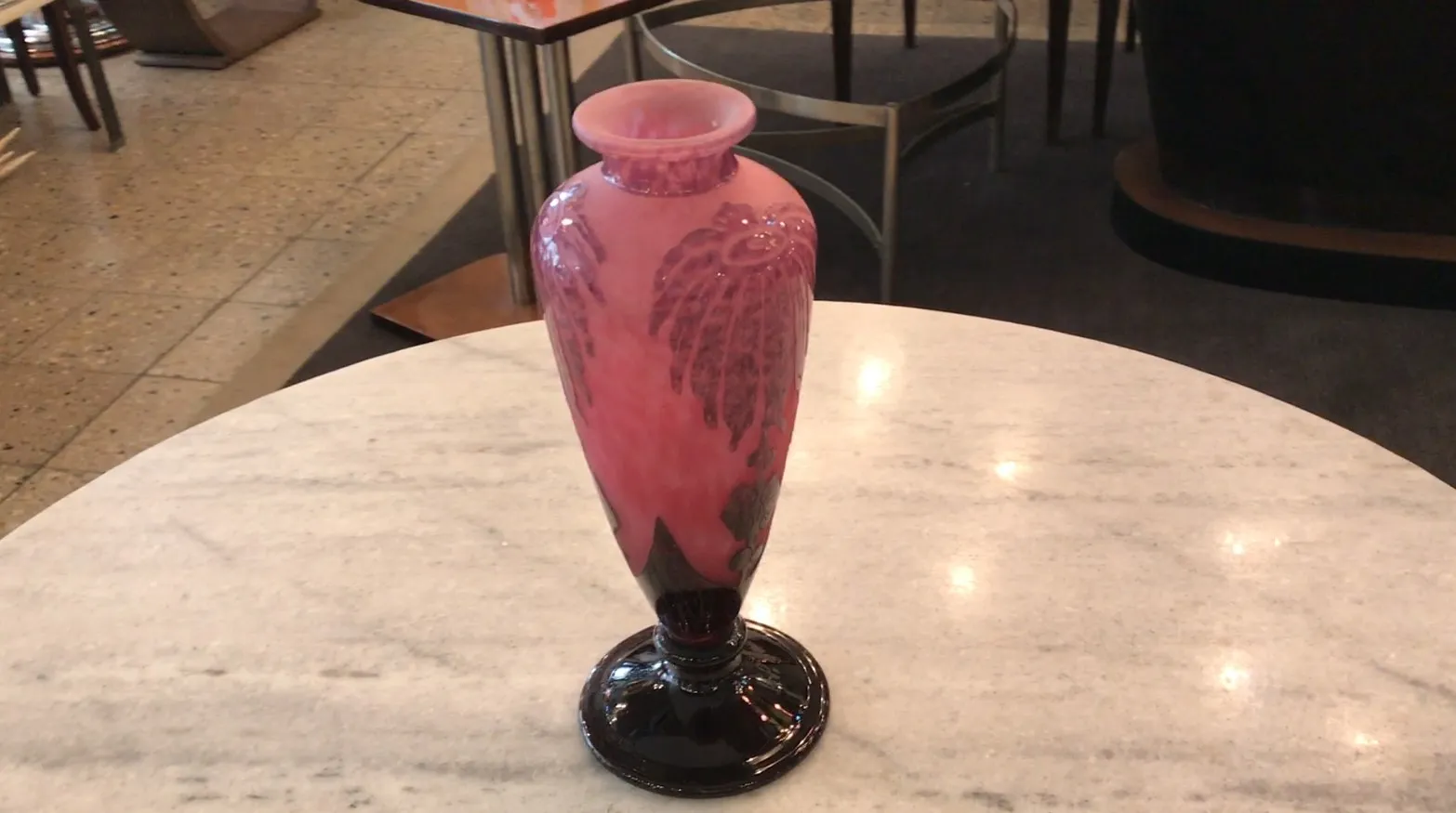 Antigua vasija de vidrio firmado Le Verre con un diseño elegante y colorido, decorando una mesa de mármol.