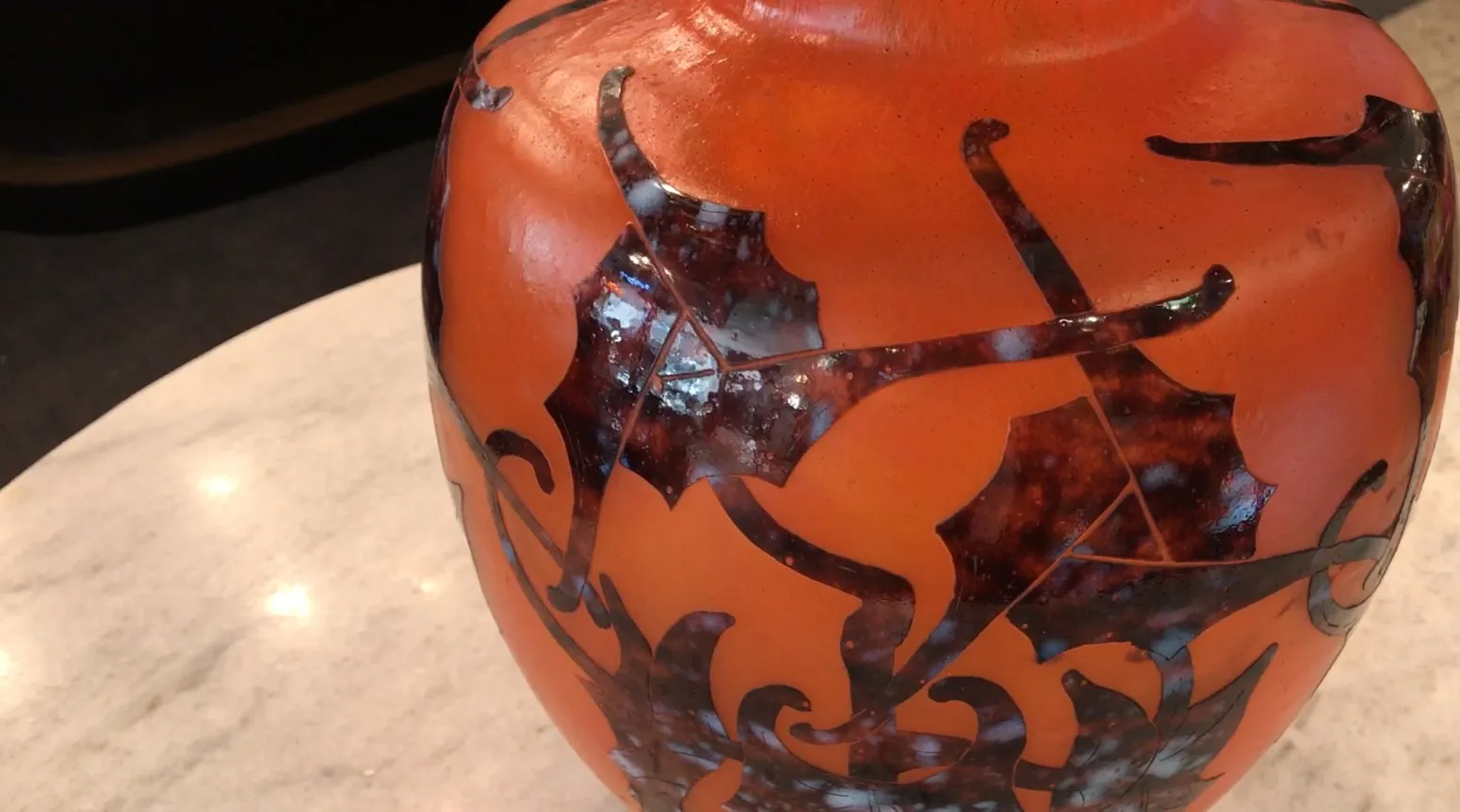 Vase en verre ancien avec un design complexe, signé, exposé dans un cadre élégant.