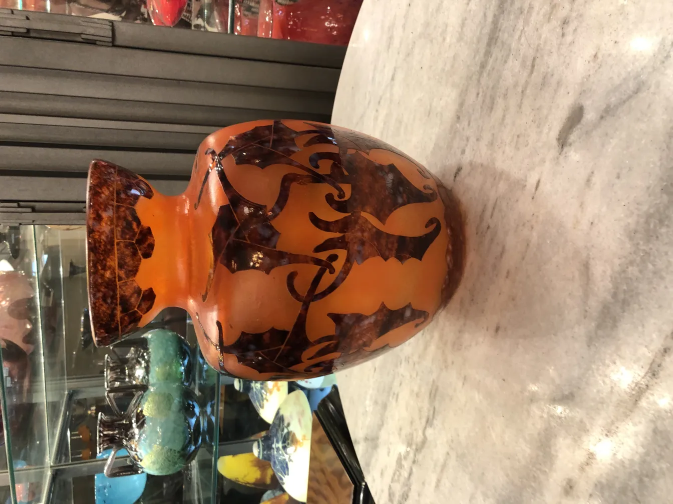 antikes Glasstück mit eleganten Mustern in Orange- und Brauntönen, ausgestellt in einem Antiquitätenumfeld