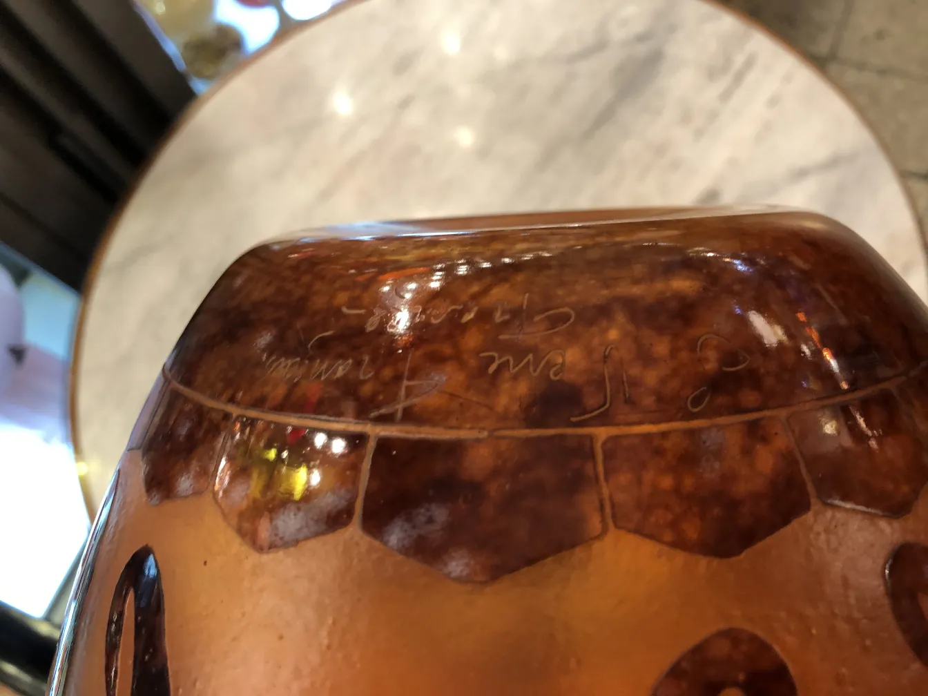 ग्लास पर हस्ताक्षरित Le Verre जिसमें गर्म विवरण और चमकदार पृष्ठभूमि है।