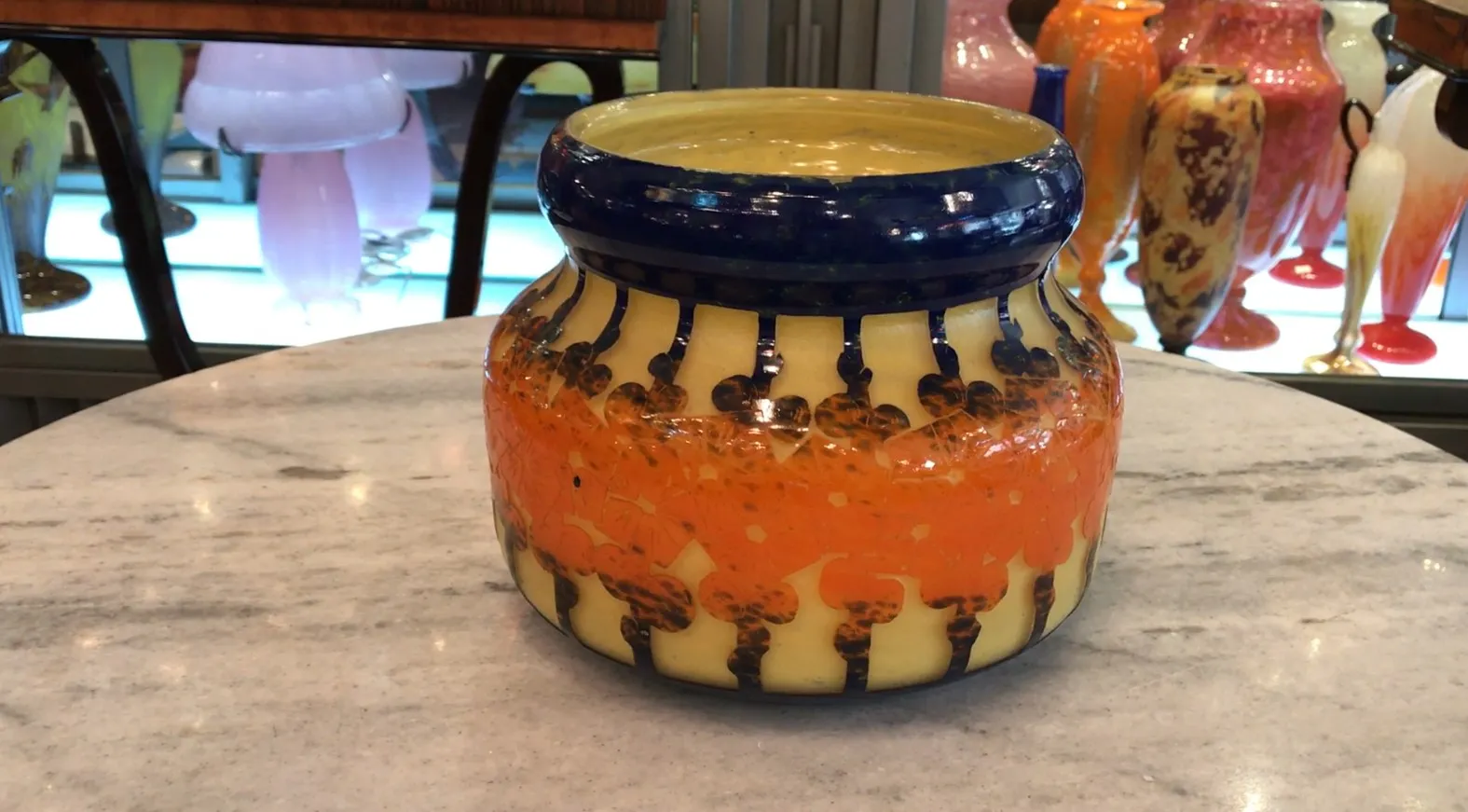 Antiga jarra de vidro assinado Le Verre com padrões coloridos.