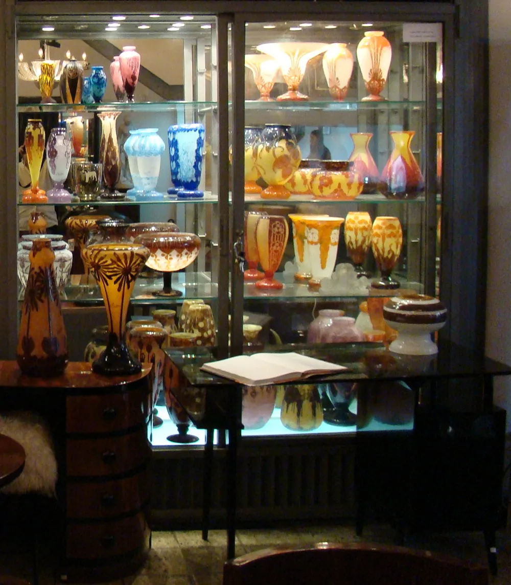 Vidrio firmado de Le Verre exhibido en vitrina, antigüedad con varios colores en el fondo.