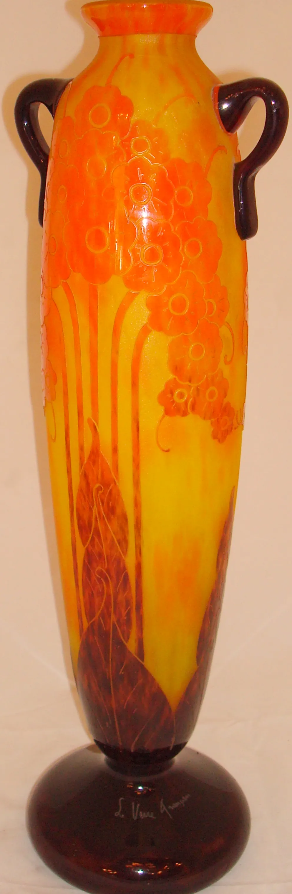 تحف زجاج موقّع le verre بتصميم زهور بألوان برتقالية وصفراء، قاعدة داكنة.