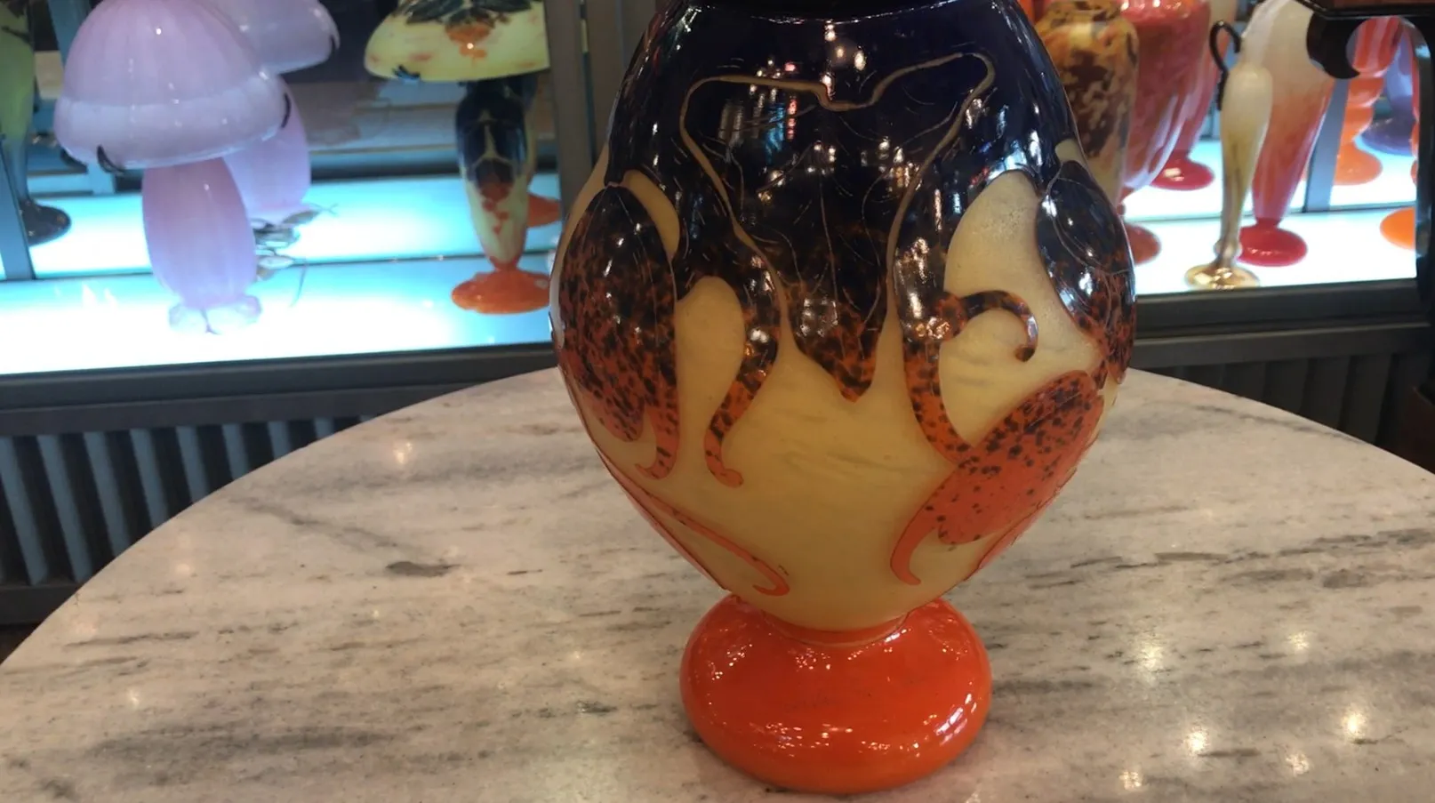 Vidrio firmado Le Verre con diseño decorativo multicolor en un ambiente de antigüedades.