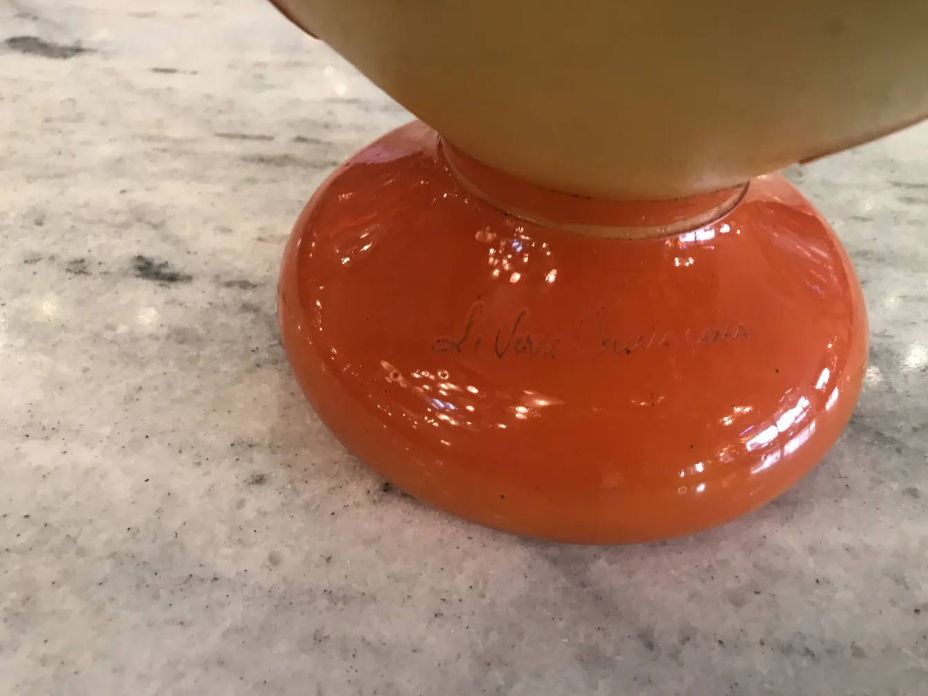 Signiertes Glas mit orangem Fuß, Detail der Unterschrift.