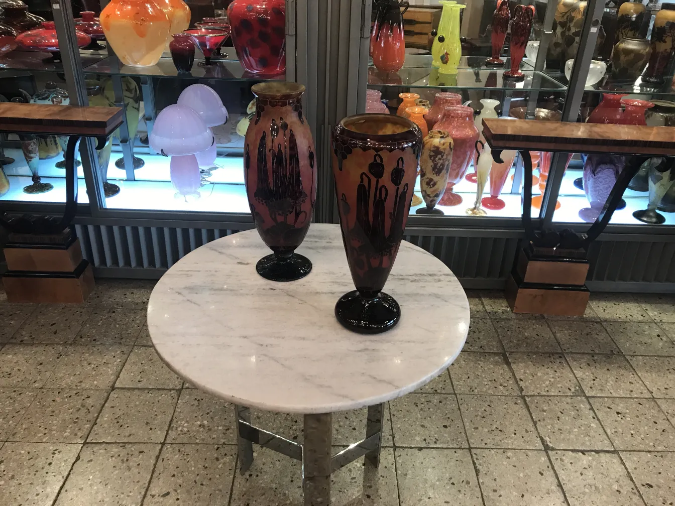 Deux antiquités en verre signé sur une table blanche.