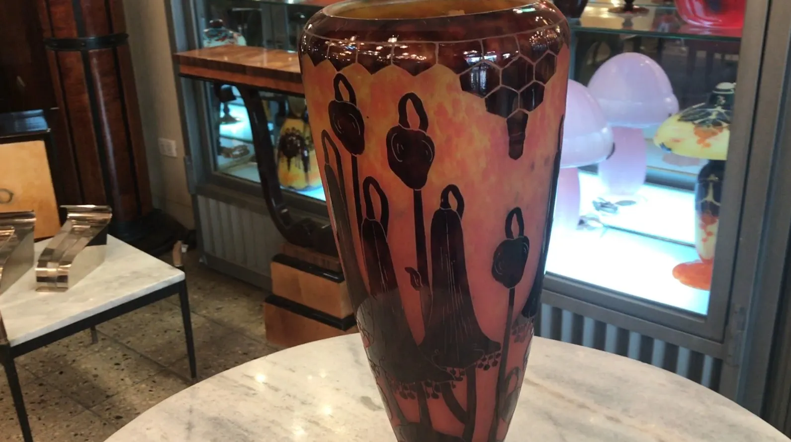 Antikes signiertes Glas Le Verre mit warmen Farben, in einem antiquarischen Raum ausgestellt.