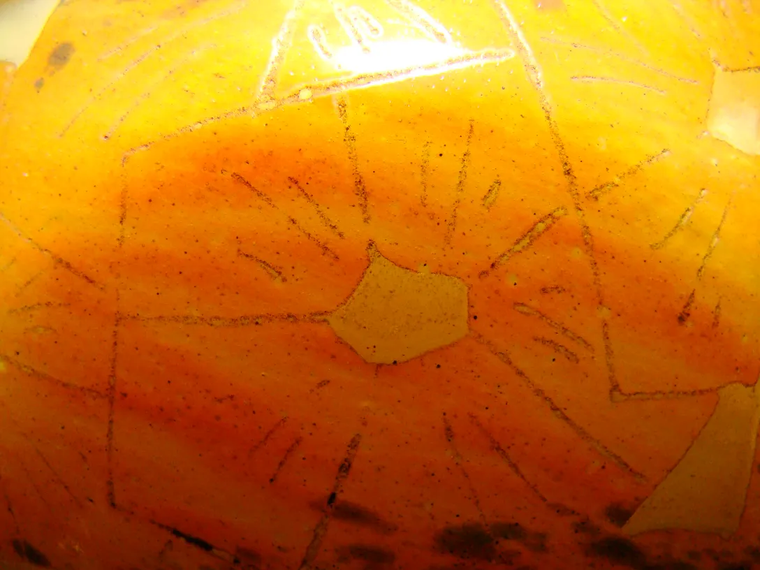 Antikes Glas mit gelbem Design und Linien, heller Hintergrund.