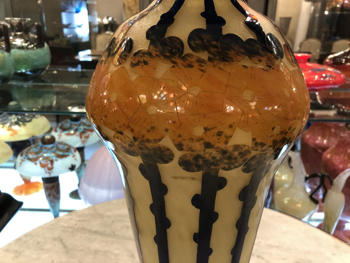 عرض زجاج موقّع قديم le verre بتصميمات بلون البرتقالي والأزرق الداكن.