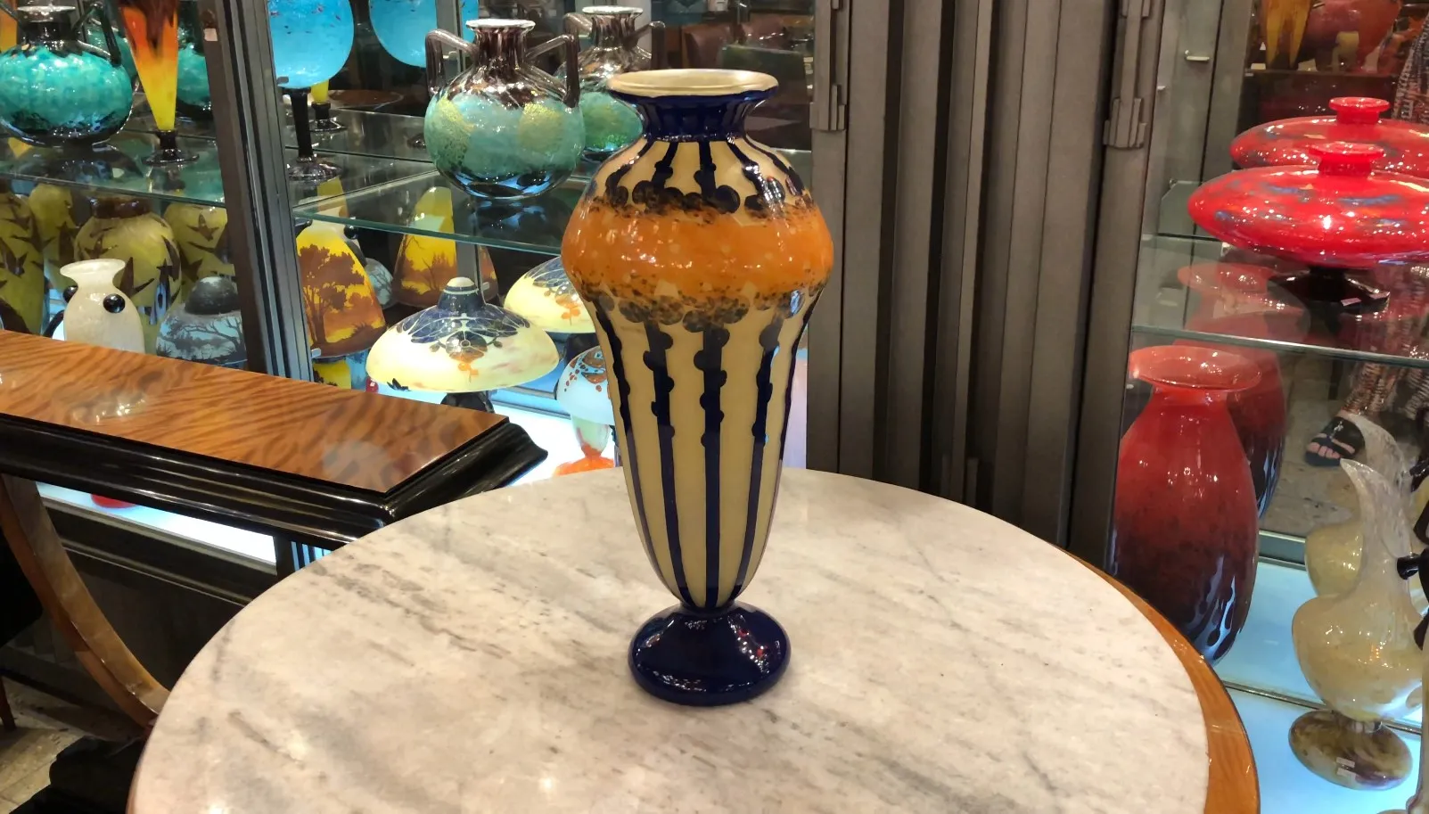 Antike Vase aus signiertem Glas, die markante Farben und Design im Hintergrund zeigt.