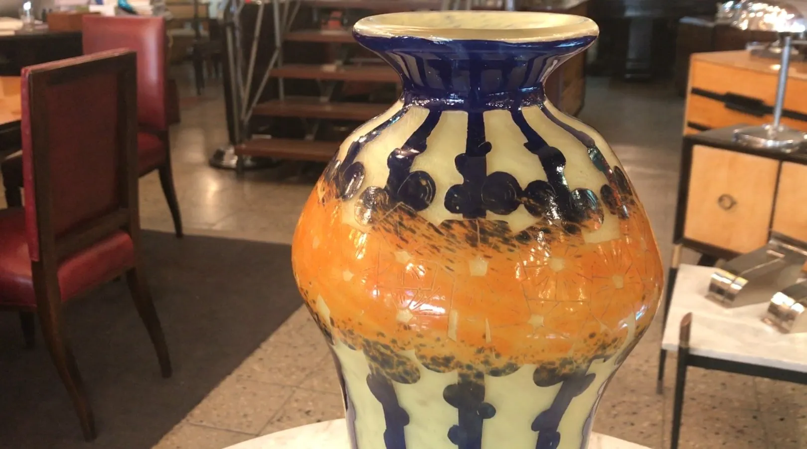 vase in vetro firmato con motivi arancioni e blu tra mobili antichi