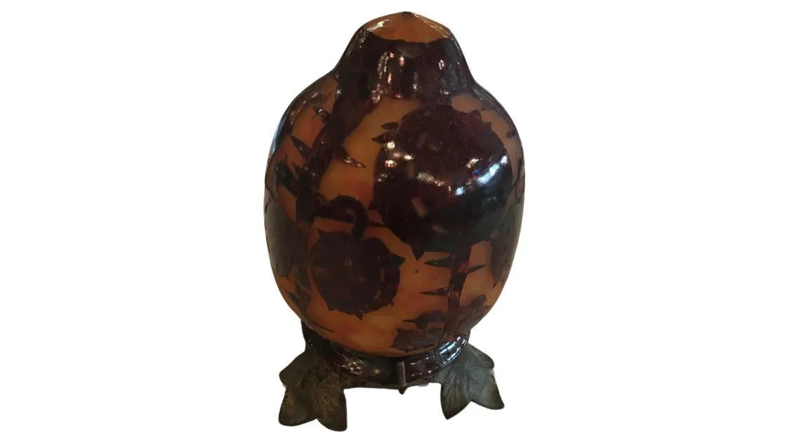 Verre ancien avec motif floral dans des tons bruns et orange, reposant sur une base décorative.