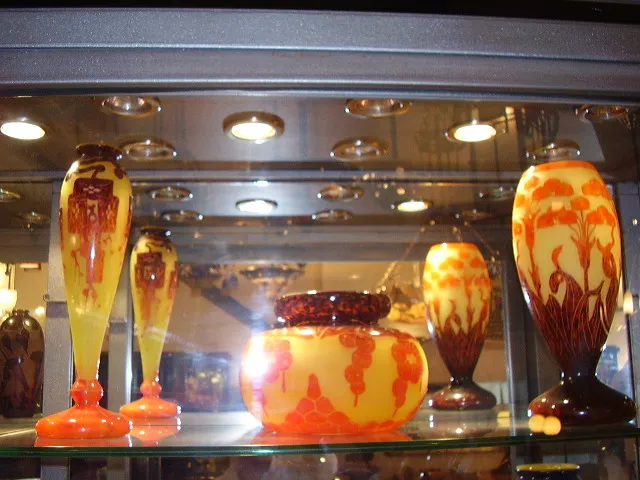 Vidro assinado Le Verre antigo com desenhos coloridos em uma vitrine.