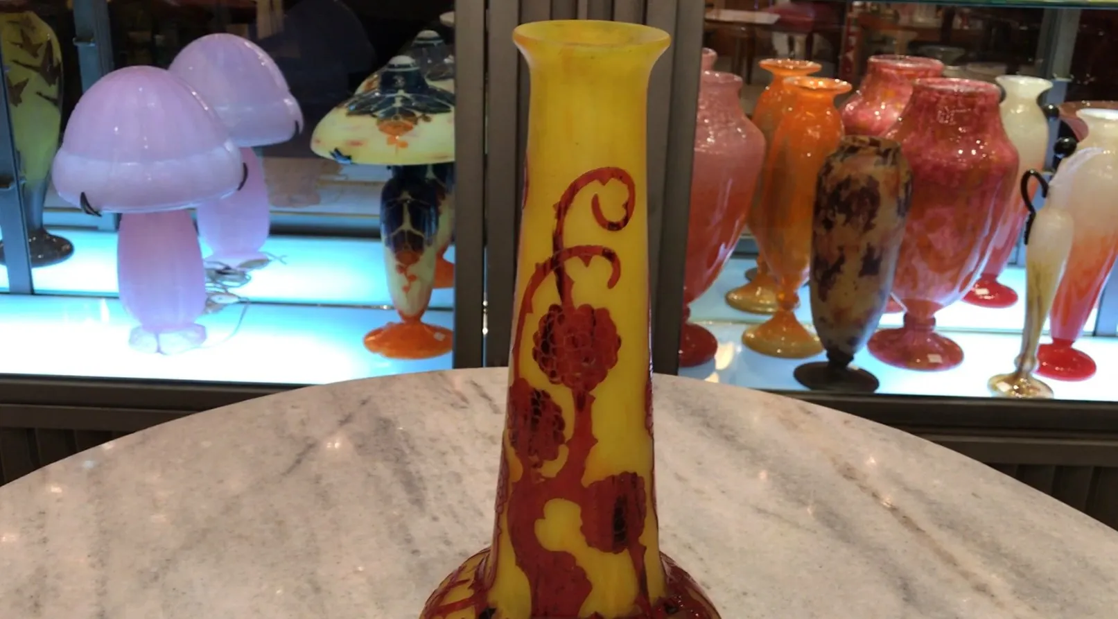 Vaso in vetro giallo con design intricato, sullo sfondo di antiquariato