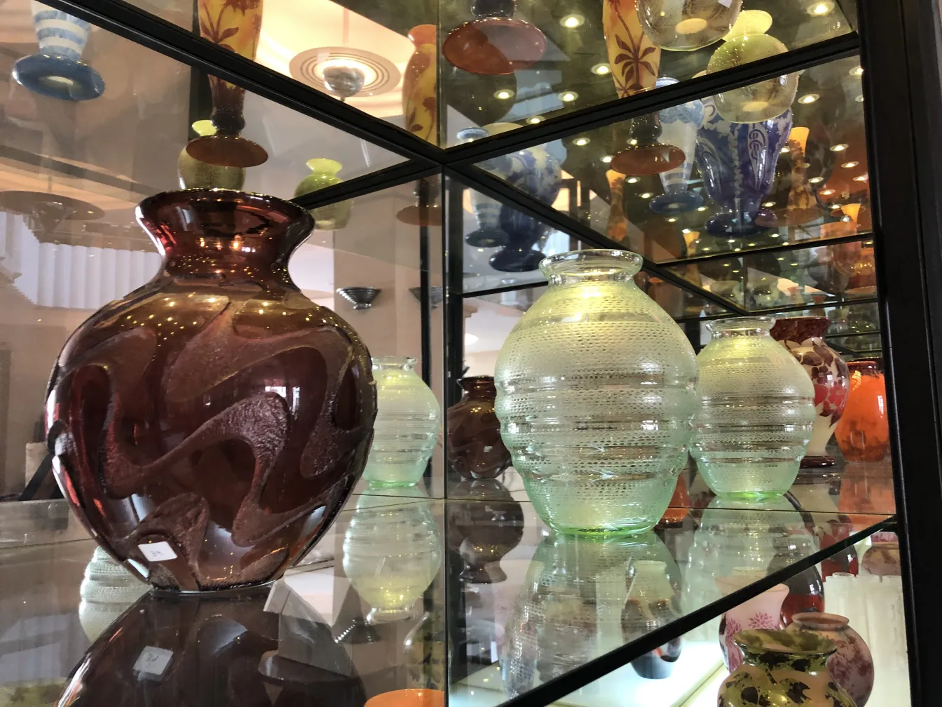 Signed glass vase with fluid designs displayed in showcase