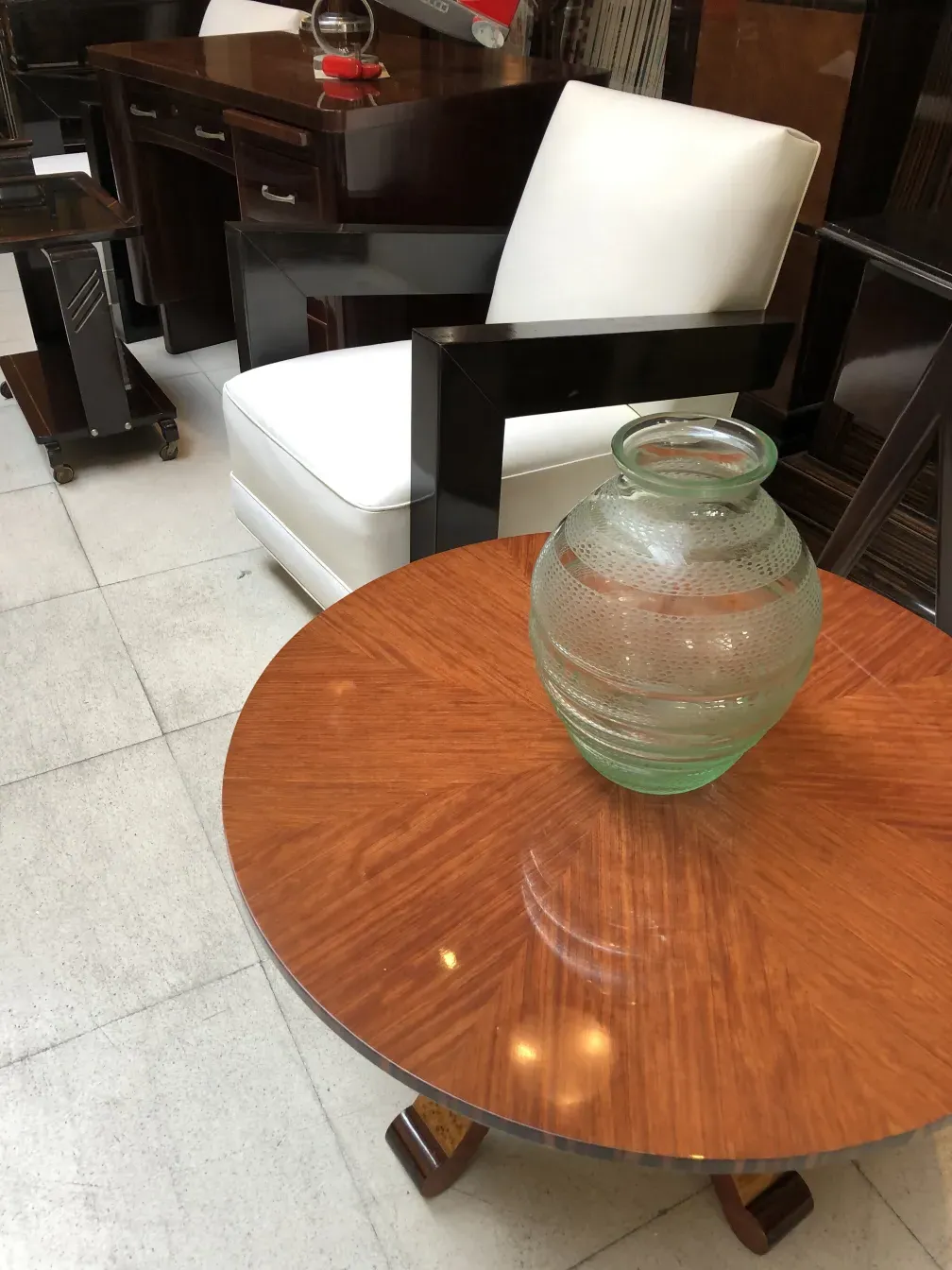 Signiertes Glas von Daum Nancy auf einem Holztisch, mit weißen Stühlen im Hintergrund.