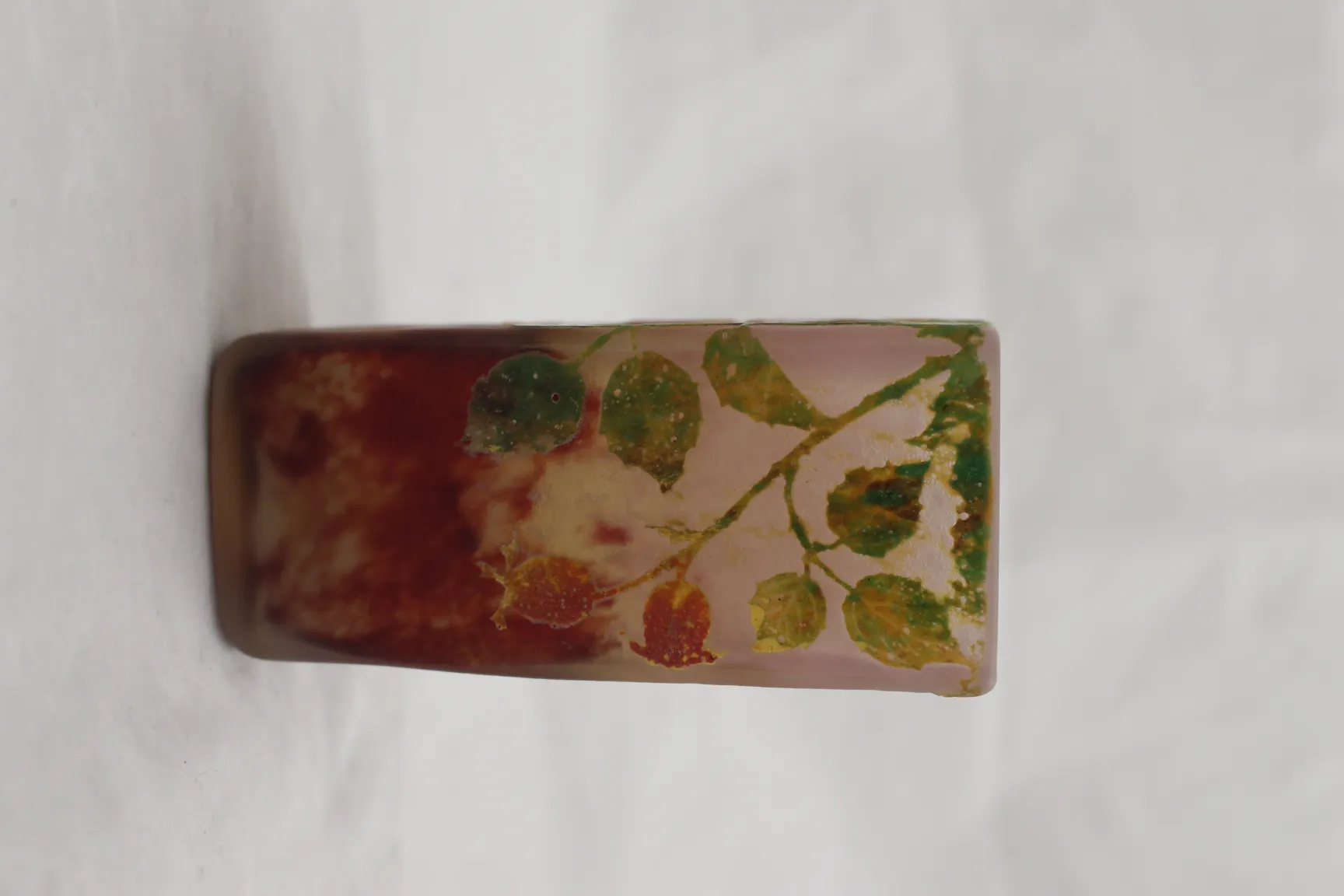 Antique signed Daum Nancy glass decorated with green and red leaves, light background.