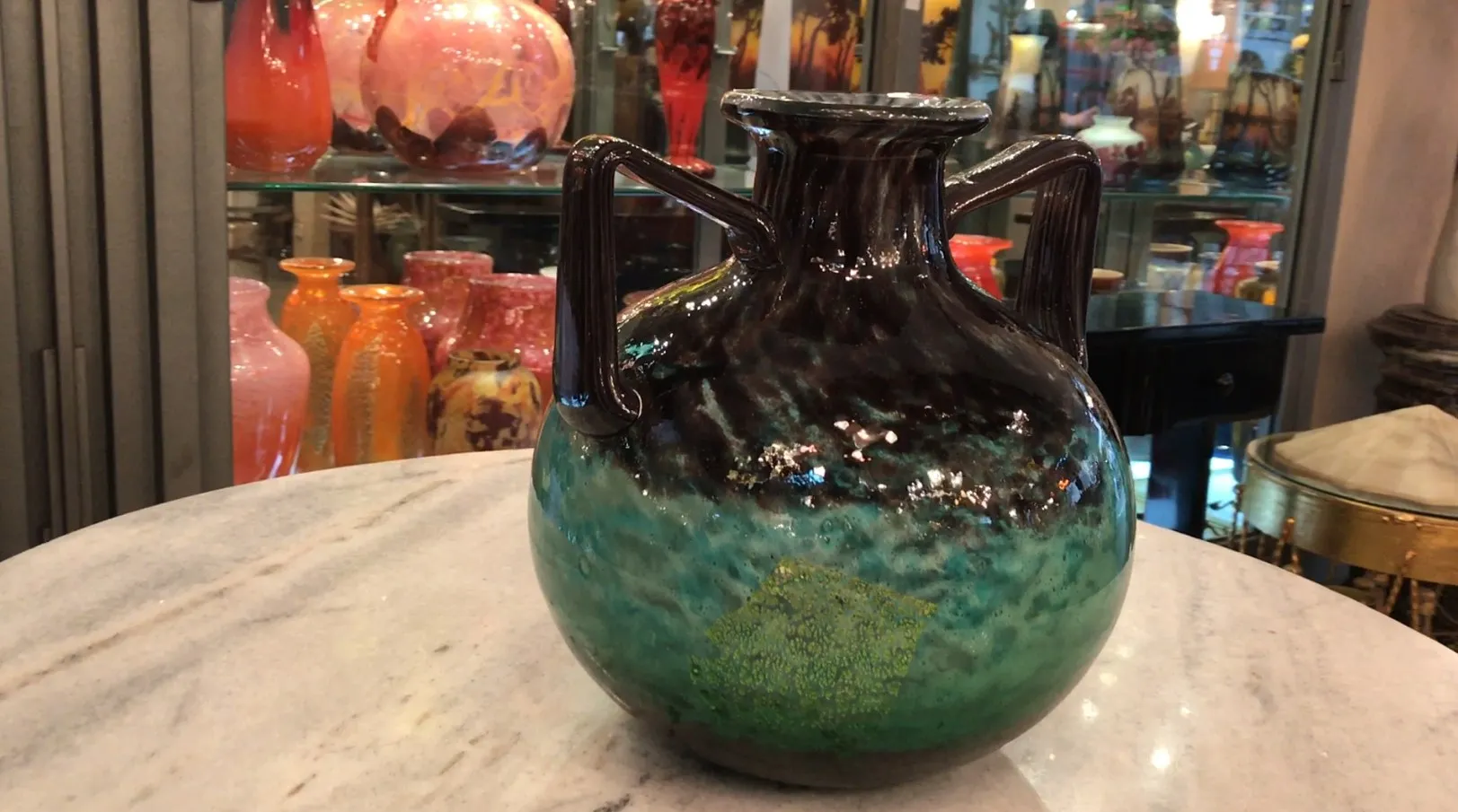 Glass jug in green and dark shades, decorative item.