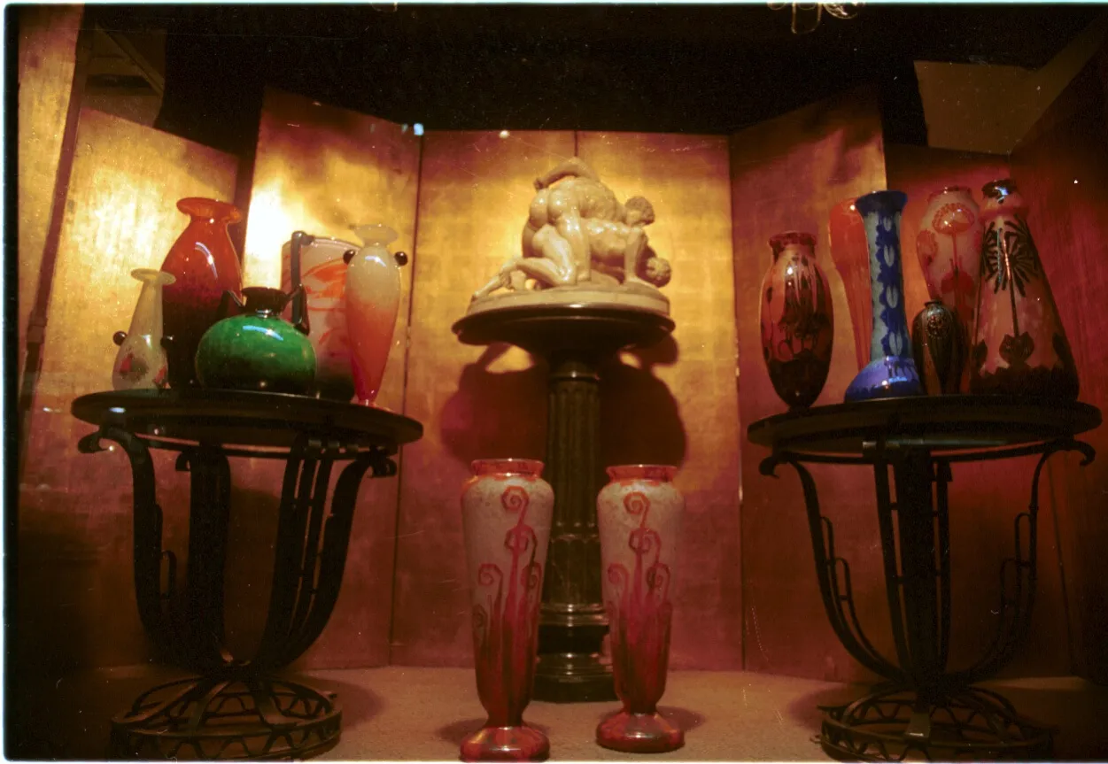 Two antique glass vases with red and pink embellishments displayed in a dark showcase.