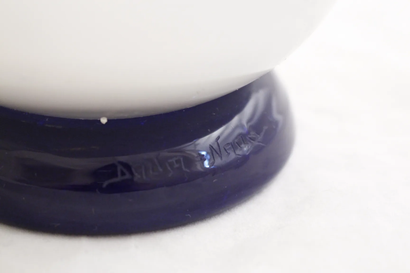 Vidrio firmado Daum Nancy con base azul y detalles en blanco.