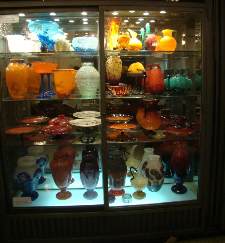 Display of antiques featuring signed glass Daum Nancy in various colors