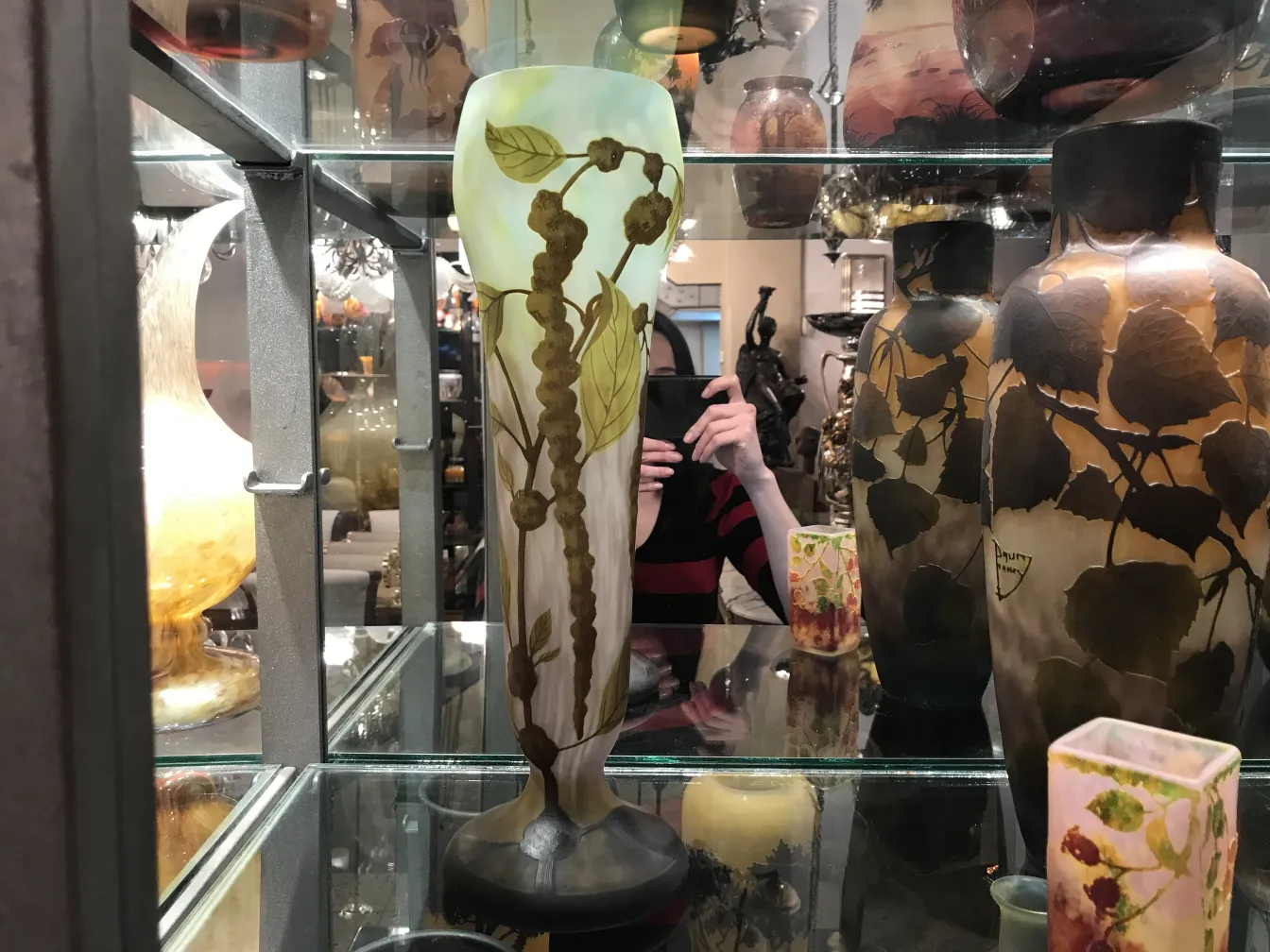 Vaso de vidro assinado Daum Nancy com folhas e flores em um ambiente antigo.