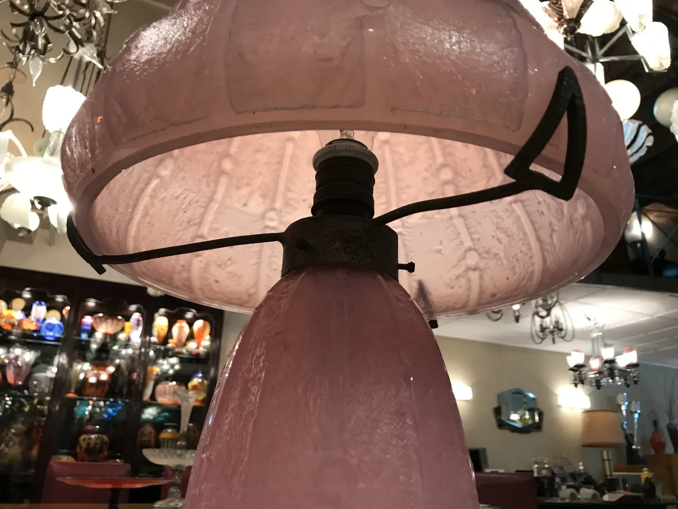 Lampada antica con paralume in vetro rosa, atmosfera vintage.