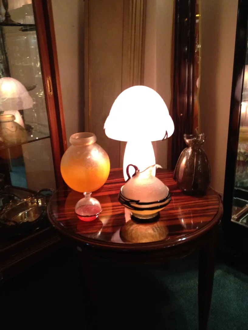Antique signed glass by Daum Nancy, featuring an elegant shape and color accents, surrounded by decorative items.