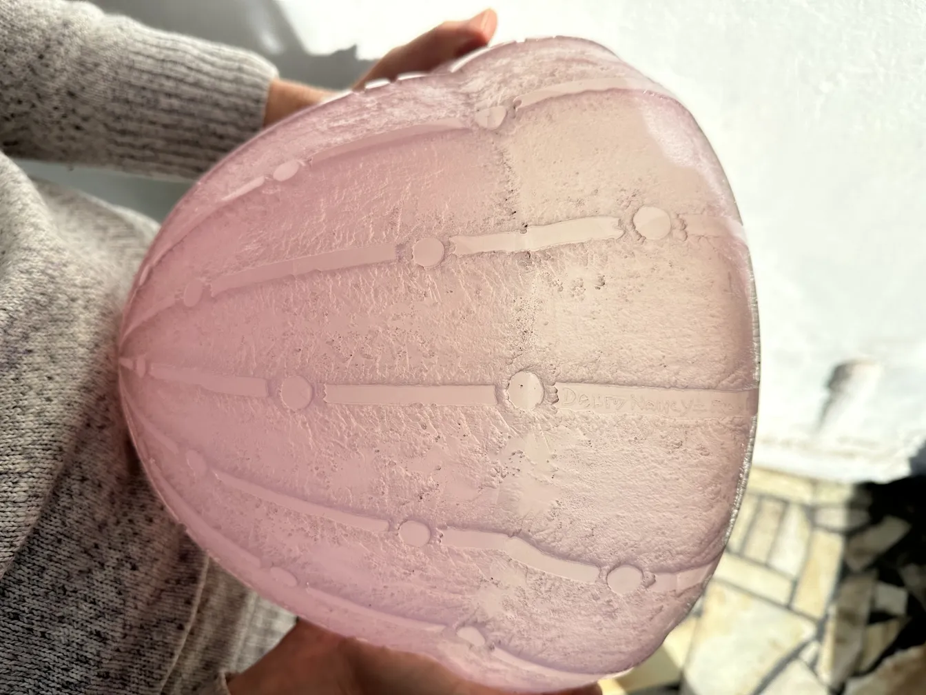 Vidrio antiguo con firma, tonos rosas, diseño elegante, fondo claro.