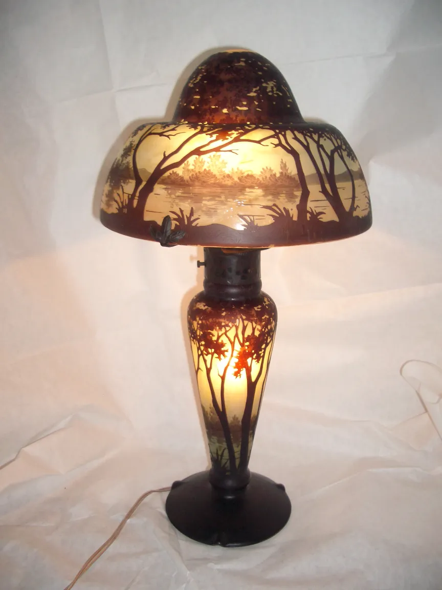 Belle lampe ancienne avec des détails en verre signé, illuminée de l'intérieur, créant une atmosphère chaleureuse.