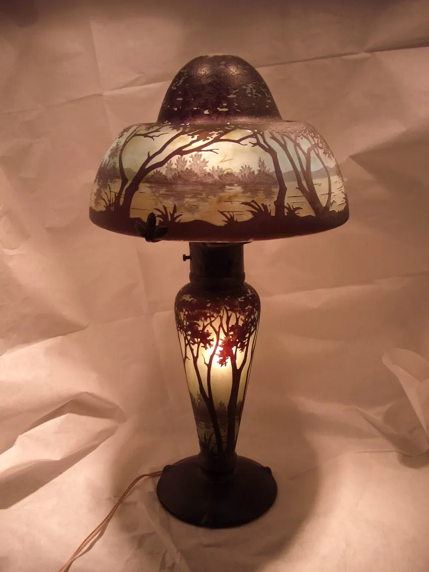 Antique lamp featuring signed glass Daum Nancy, illuminated, with landscape details.