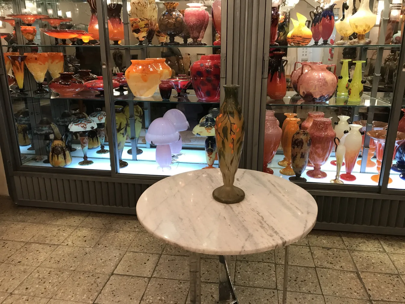 达姆南希签名玻璃花瓶，陈列在展示柜中，周围有各种装饰品。