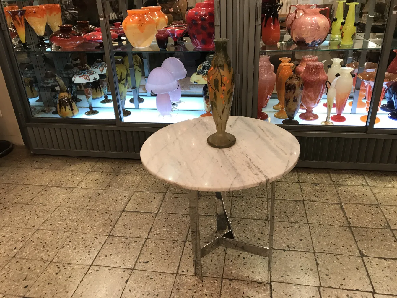 Vase de vidrio firmado Daum Nancy con decoración colorida, en un ambiente con otras antigüedades.